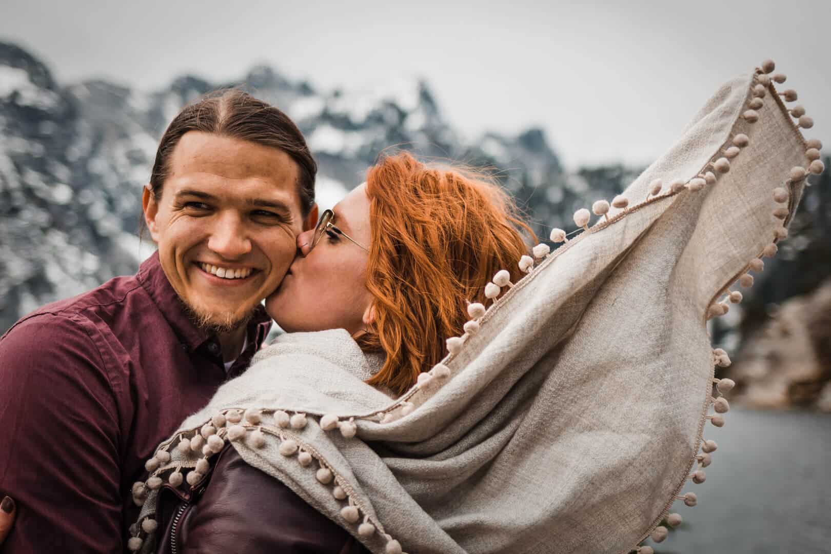 couple kissing in front of mountains