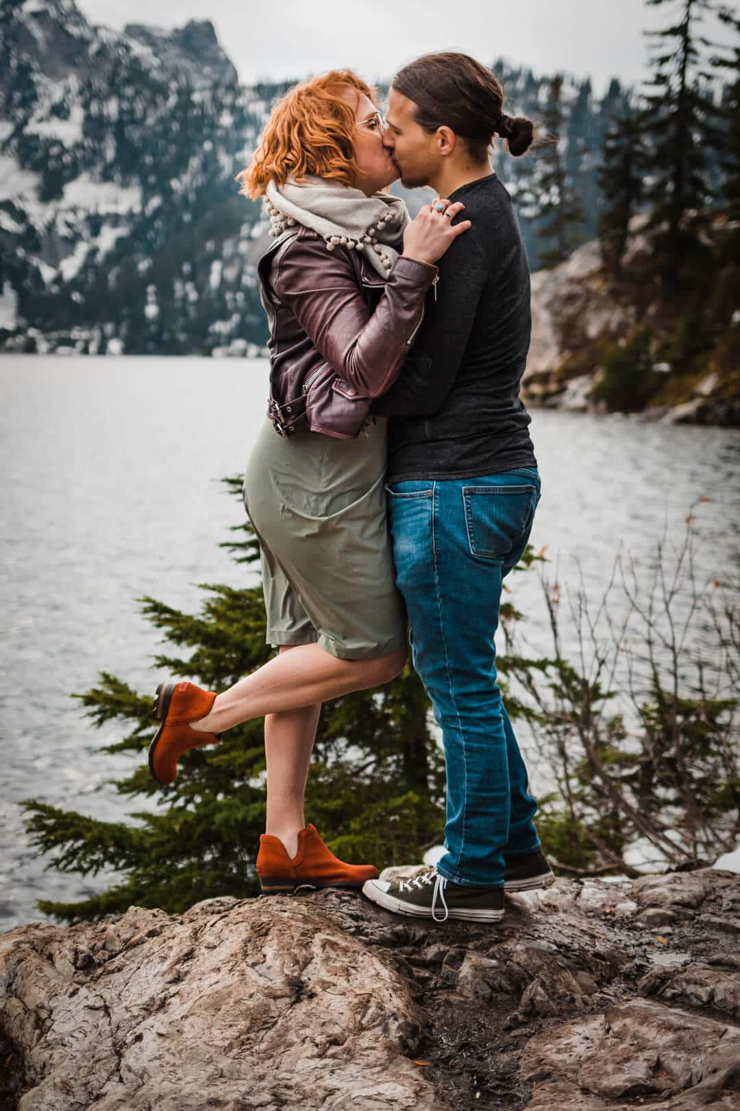 couple kissing in front of mountains and lake