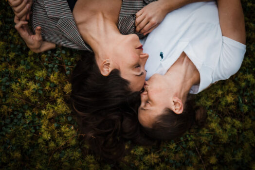 couple laying on moss in forest