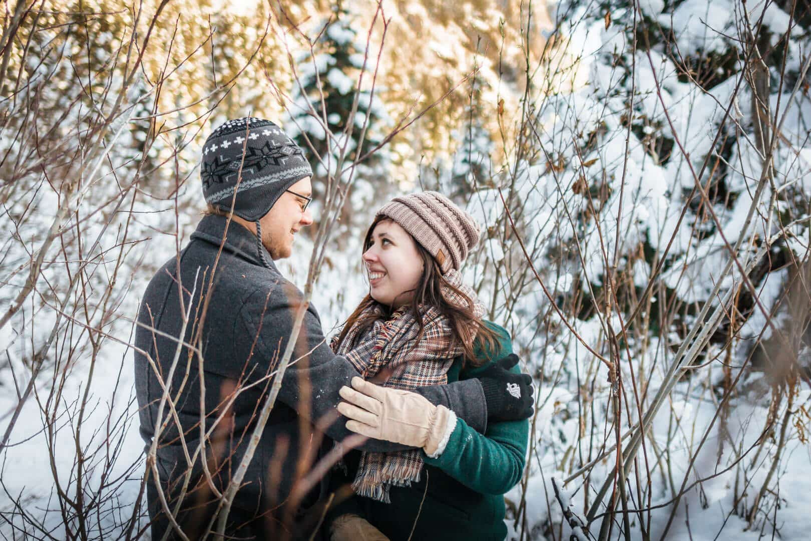 couple hugging in snow with mountain behind them