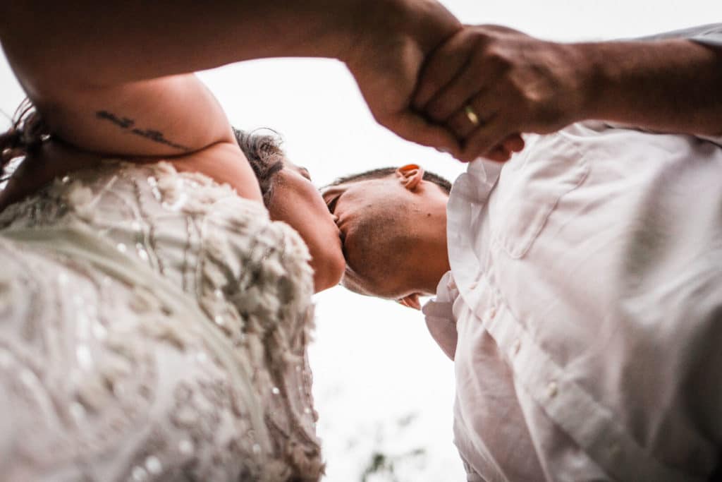 bride and groom kissing with sky above them