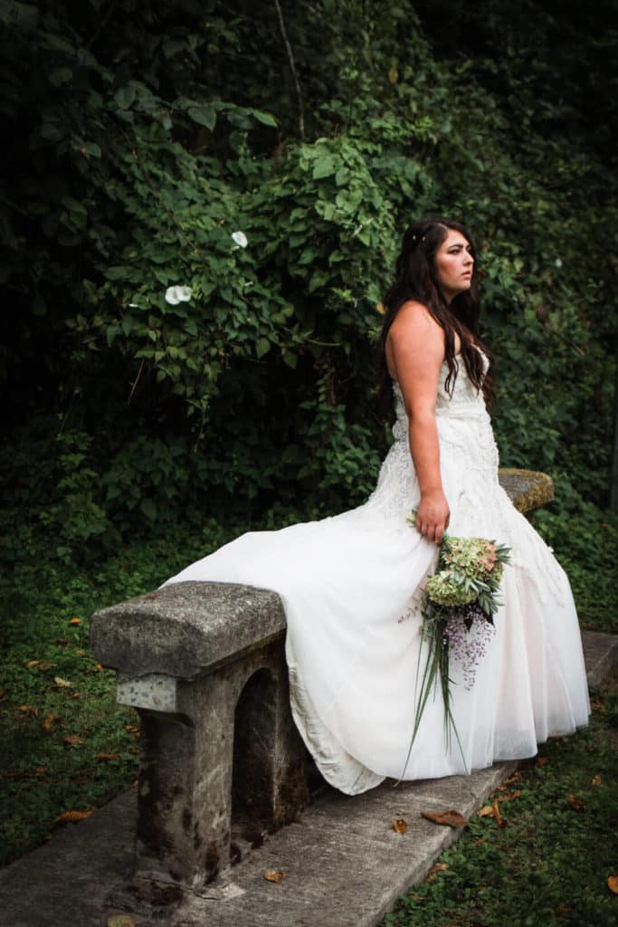 bride sitting on stone bench in forest