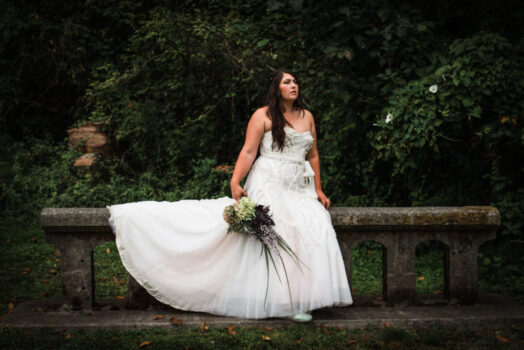 bride sitting on stone bench in forest