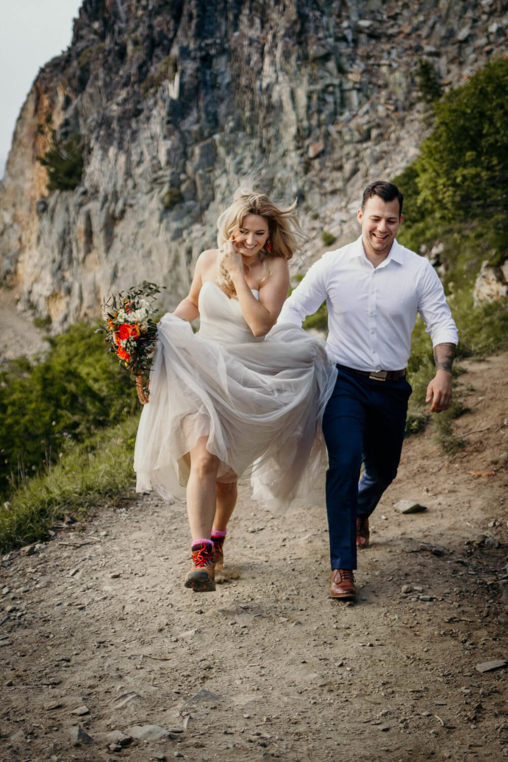 bride and groom running on mountain trail