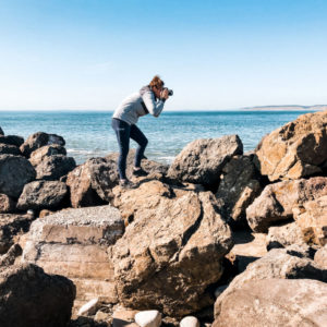 a person takes a photo standing on rocks