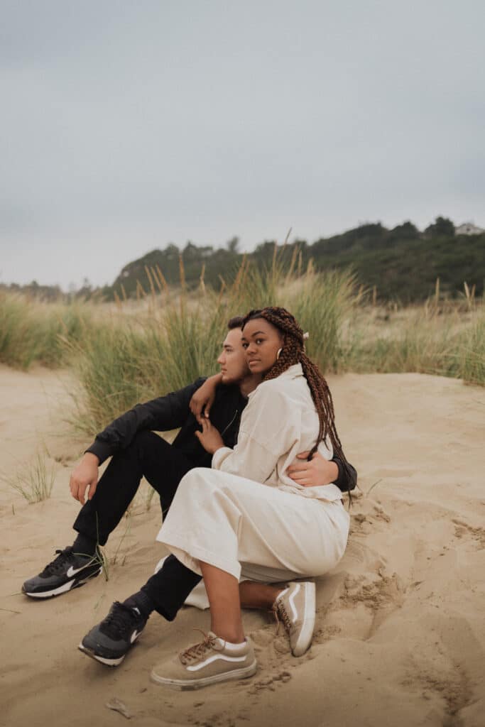 two people hugging and sitting on a beach