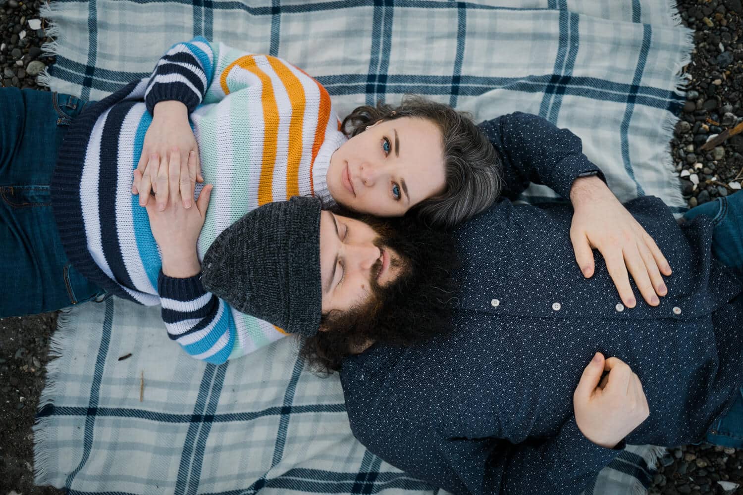 a couple laying on a blue blanket with one person looking at the camera