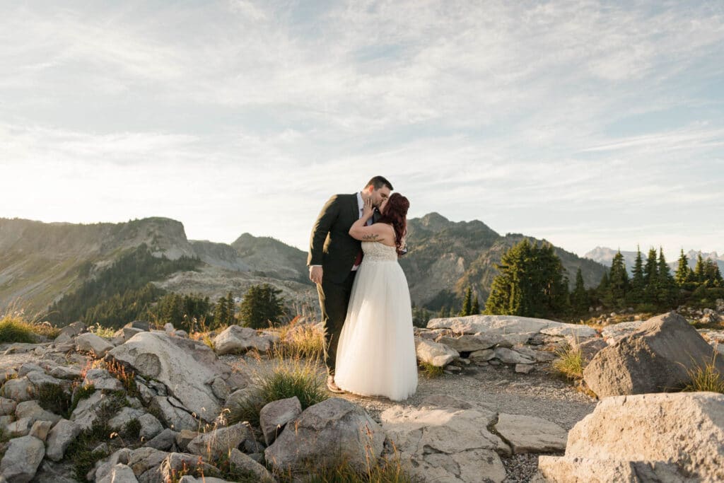 two people kiss in front of a mountain view