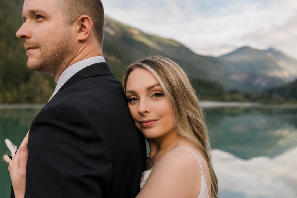 two people hug with a lake and mountains in the background